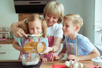 Happy grandmother with her grandchildren having fun during baking muffins and cookies