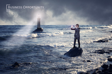 Businessman standing on a rock looking through a spyglass for business opportunity