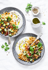 Spiced chickpeas and couscous with shepherd's salad and greek yogurt on a white background, top...