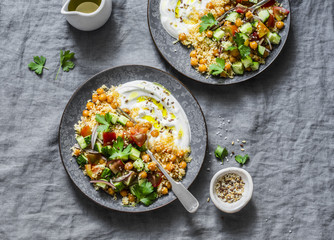Spiced chickpeas and couscous with shepherd's salad and greek yogurt on a grey background, top...