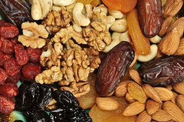 The whole space of the frame is occupied by dried fruits and nuts. In the frame there are dried apricots, prunes, almonds, cashews, raisins, cherries, walnuts, dates. View from above. Close-up. Macro.
