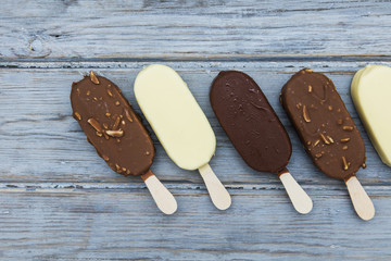 Chocolate ice cream lollies on a wooden background.