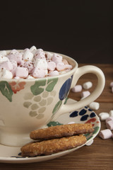 Beautiful vintage cup of homemade hot chocolate or cocoa with marshmallows, wooden table and black background. Warm sweet drink. Copy space.