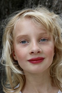 Portrait of a blonde young girl with bright red lipstick and a mysterious smile