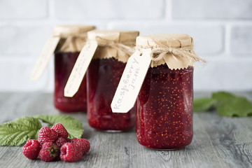 Homemade raspberry jam in glass jars on gray wooden table. © zhannaz