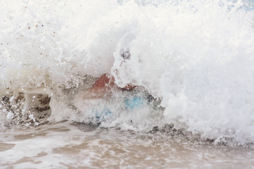 drowning man after a shipwreck, struggling with sea waves, covering him with his head.
