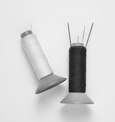 Vintage black and white skeins of thread with needles on white background.
