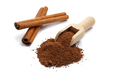 Cinnamon powder in a wooden scoop and cinnamon sticks, isolated on white background