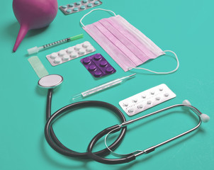 Medical equipment on blue background. Enema, blisters pills, notepad, stethoscope, syringe,...