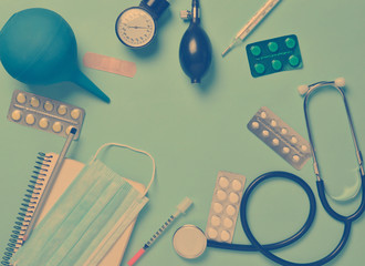 Medical equipment on a blue background. Enema, blisters pills, notepad, stethoscope, syringe,...