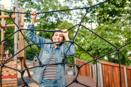Happy fun woman in an adventure rope park at children playground