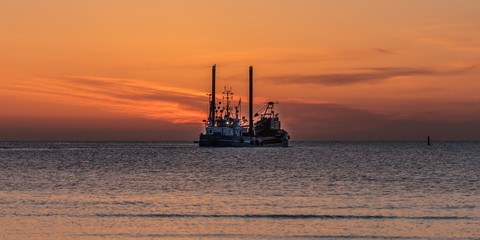 Obraz premium baggerschiff bei sonnenaufgang