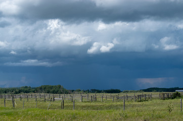 Fototapeta na wymiar Wood Corral with approaching storm clouds, Saskatchewan, Canada.