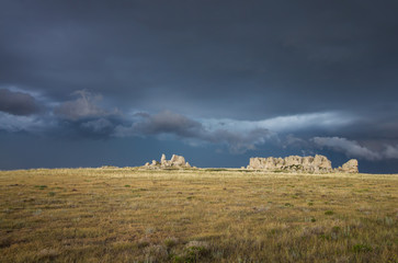 A dark and stormy sky behind a rocky ridge on the North American prairie.