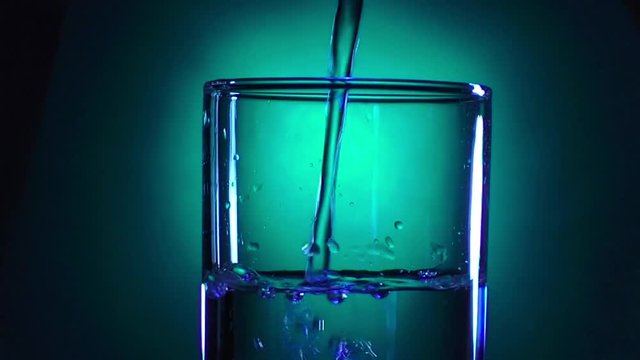 A glass of clear water on a bright background with a gradient fills to the brim in blue and green tones