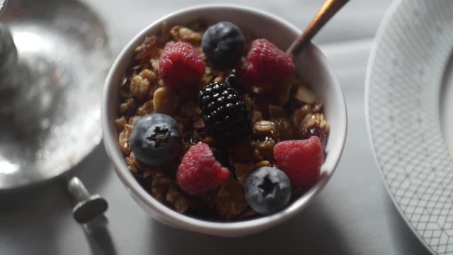 A breakfast parfait with granola, raspberries, blueberries, and blackberries.