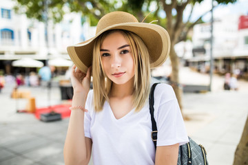 Beautiful young woman in summer hat walking in the city.