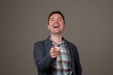 Handsome excited european young man smiling pointing fingers at you.