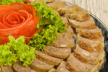 Meat sliced on a mirror dish decorated with verdure.