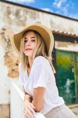 Portrait of a beautiful caucasian woman on summer terrace with smile in summer hat