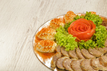 Obraz na płótnie Canvas Meat sliced on a mirror dish decorated with verdure.
