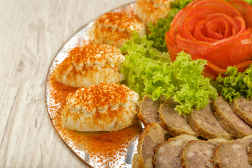 Meat sliced on a mirror dish decorated with verdure.