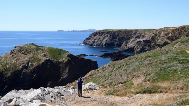 Man walking to a viewpoint to take a photo of the view along the coast