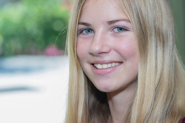 Portrait blonde young girl smiling with outdoors through window in background