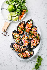 PERUVIAN FOOD. Choros a la chalaca. Big mussels, choros zapatos seasoned with purple onion, tomatoes, corn and lemon. Top view, white background. Traditional peruvian dish