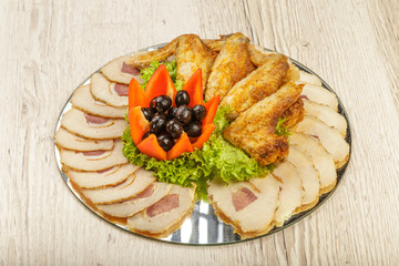 Dish from tartlets chicken wings and meat sliced with the presence of lettuce leaves.