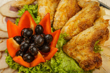 Dish from tartlets chicken wings and meat sliced with the presence of lettuce leaves.