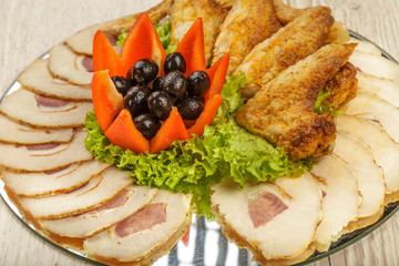 Dish from tartlets chicken wings and meat sliced with the presence of lettuce leaves.