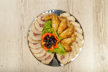 Dish from tartlets chicken wings and meat sliced with the presence of lettuce leaves.