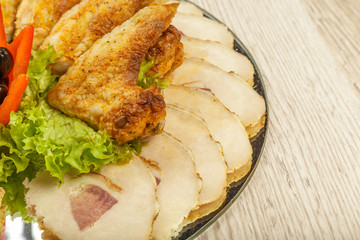 Dish from tartlets chicken wings and meat sliced with the presence of lettuce leaves.