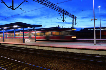 Dworzec kolejowy i pociągo wieczorem i nocą oświetlone lampami. - obrazy, fototapety, plakaty
