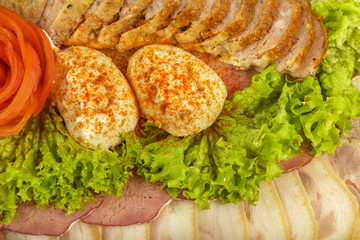 Meat sliced on a mirror dish decorated with verdure.