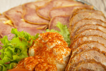 Meat sliced on a mirror dish decorated with verdure.