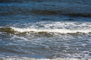 Sea waves crashing against stones lying by the shore. Water and stones on the beach