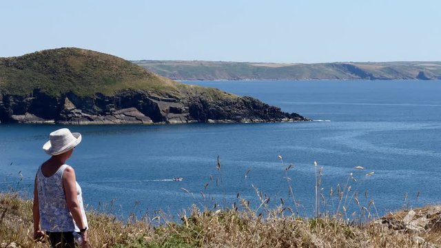 Lady walking away, on the coast path, over looking St Brides Bay on a summers day.