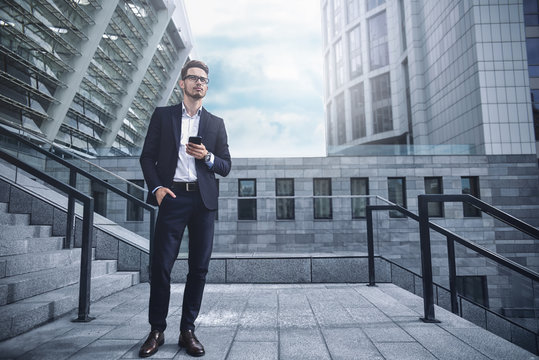 Business man stand at street holding a smartphone in office park - Powered by Adobe