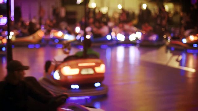 Defocused view of multiple driving bumper cars at attraction amusement park nighttime view of funny atmosphere at the amusement park