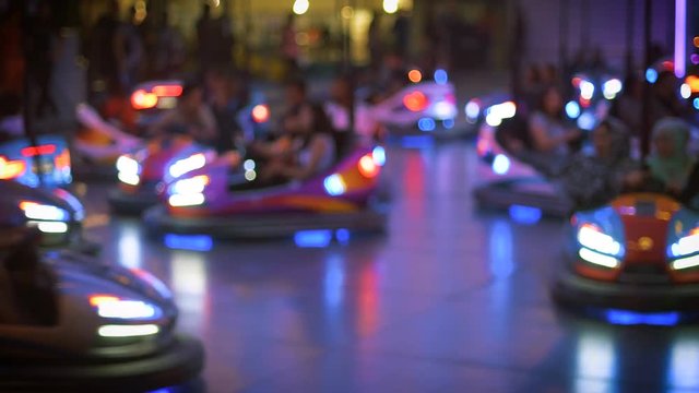 Funny atmosphere at attraction amusement park with defocused view of multiple driving bumper cars 