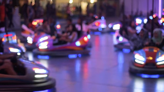 Time-lapse fast motion of nighttime view of funny atmosphere at the amusement park with multiple bumper cars accidents happy people silhouettes  - real game