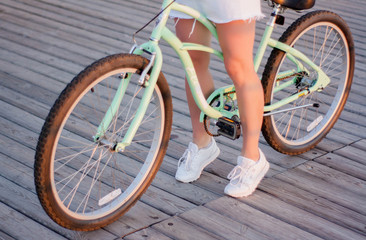 Close up, beautiful young woman with bicycle, handlebar, wheels, body part. Hands on the handlebar