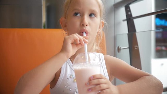 Little girl child in cafe drinking milk cocktail cacao with milk. Child drinks a milkshake sits in a cafe.