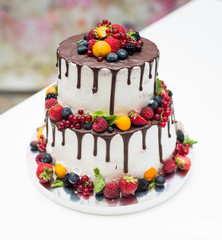 White wedding cake with flowers and leaves on black background isolated.
