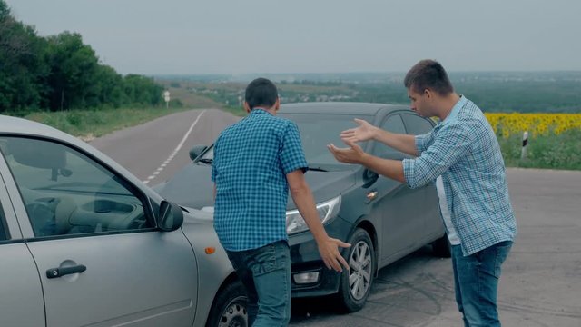 Two drivers argue about blame for accident by the side of damaged. Two male drivers argue over who is to blame for traffic accident. The concept of traffic.