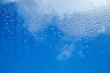 Drops of water on a glass against a cloudy sky background. Seamless texture