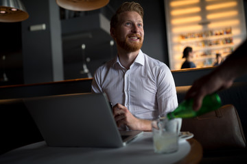 A handsome young businessman spends his time in a city bar.