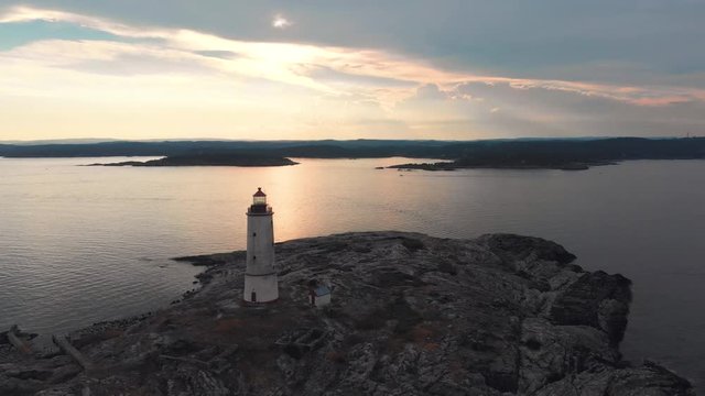 Continued Aerial orbit shot of Tiny Torungen Lighthouse on a cloudy day right before sunset showing the mainland of Norway